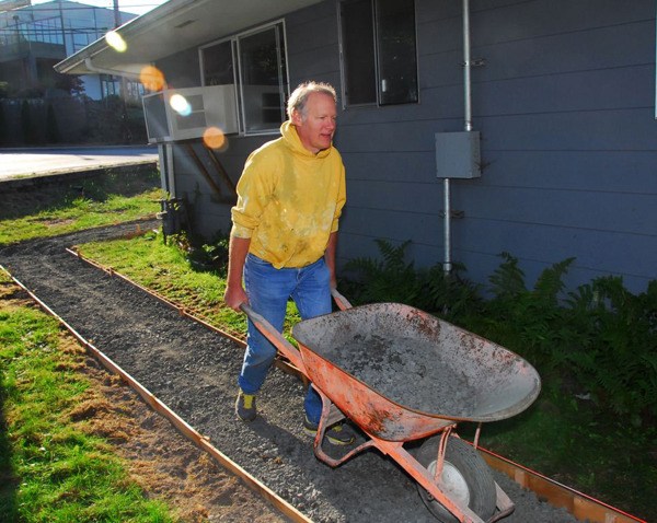 Dave Frederick pushes a wheelbarrow during work outside the Coffee Oasis-Poulsbo location. Donations