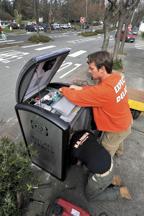 Lydel Construction President Todd Smith (standing) and employee Mickey Jacob install one of six new solar trash compactors on State Route 104 in Kingston on Wednesday.