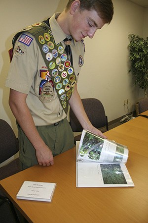 Luke McMillan flips through his Eagle Scout project binder.