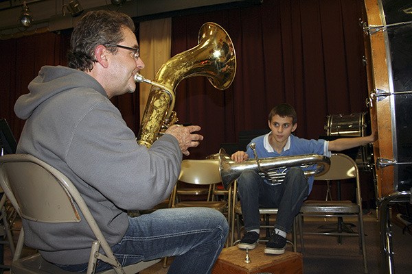 Band director Benson Cleverdon plays notes for profoundly deaf student Trenton Eash who feels the vibrations on a drum and sound box.