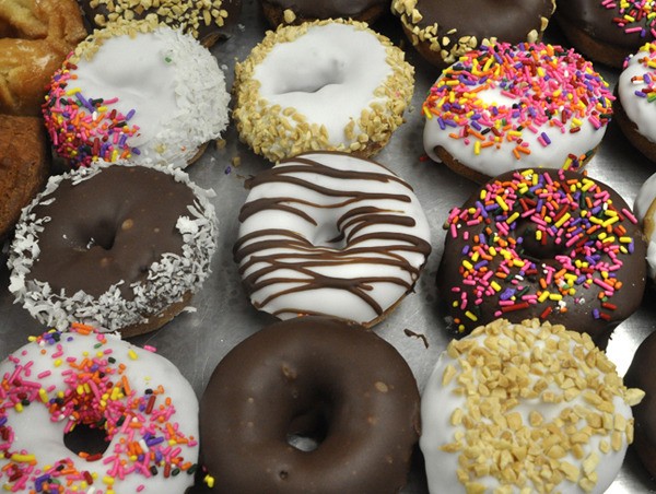 Donut maker Reed Burchard’s work sets finished in varied sprinkles and frosting combinations ready for Dippity Donuts’ customers Wednesday morning.