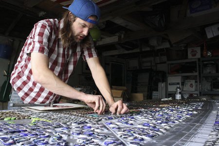 Bremerton artist Dave Ryan works on a bottle cap mosaic at his garage studio.