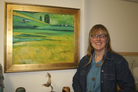 Gwen Guidici of Bremerton in front of one of her oil paintings at Old Town Custom Framing and Gallery in Silverdale Monday. Sixteen of the Bremerton artist’s landscape paintings were recently turned into a jigsaw puzzle as a Mac App.