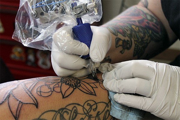 Erin Ashleigh of The Clinic Tattoo shop in Bremerton creates artwork on a client’s arm. She’s known for bold