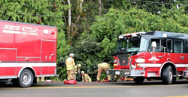 Firefighters bring a woman up from the site where a SUV rolled down an embankment near Miller Bay Road