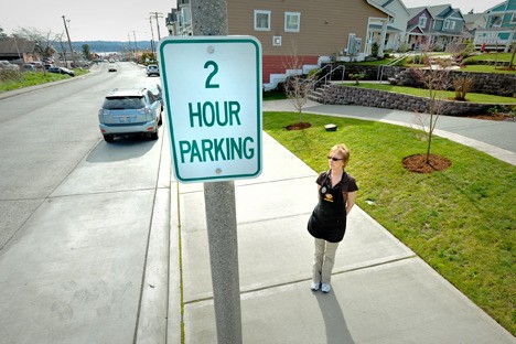 Jak’s Cafe owner Julie Krucek stands by a two-hour parking sign she lobbied to have the city install on Jensen Way. A lack of parking options is a ongoing point of contention for residents and business owners in the Poulsbo Place II neighborhood.