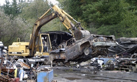 A backhoe is used to clean up debris at a Clear Creek Road property Monday