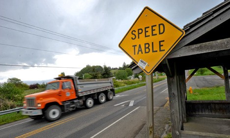 A county dump truck rolls over an asphalt speed table on Hansville Road. Speed tables have been a source of contention in the North End town since they were installed three years ago.