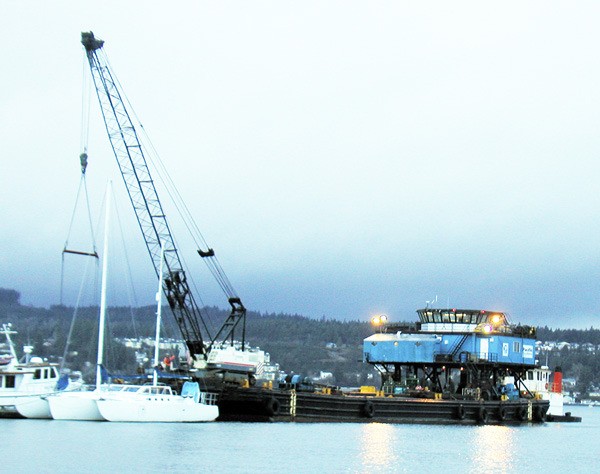 A barge-mounted crane works to raise a sunken boat off the Port Orchard Railroad Marina dock.