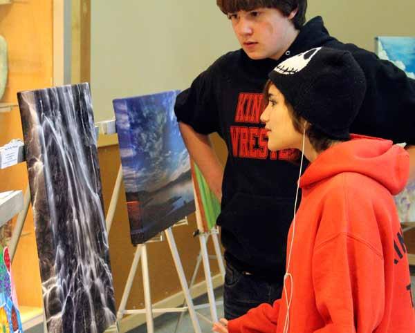 Carmen W. and Julian Leigh stop to appreciate photography by Mark VanHuis at the entrance of the North Building during the 10th annual Festival of The Arts May 23 at Kingston High School.