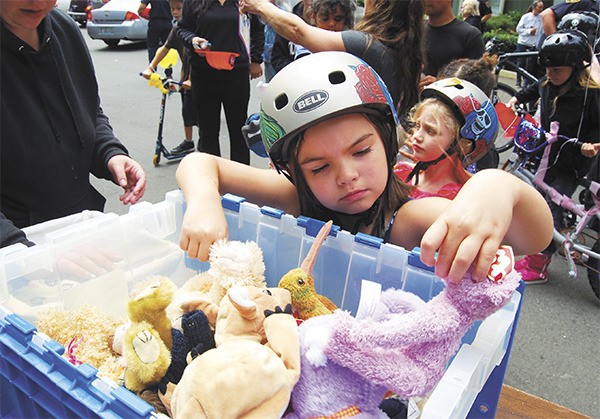 A young resident of Heritage Apartments ponders over what stuffed animal to choose. She wore a bicycle helmet given to her and other kids during a Port Orchard Police community event July 23.