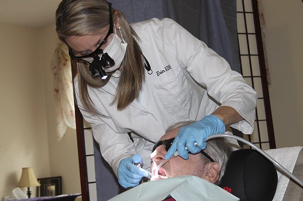Erin Pocuis cleans Bill Nickerson's teeth at his residence.