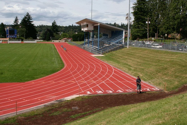 A Bremerton School District groundskeeper waters the grass next to the new track at Memorial Stadium. The project