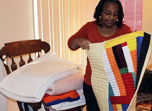 Delia Pettway-Thibodeaux opens up a quilt she made using various scraps of clothing. The Silverdale resident uses skills she picked up in her native Gees Bend