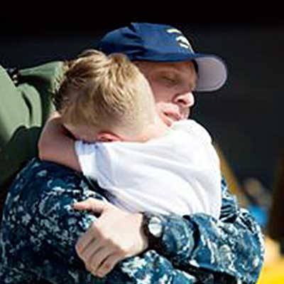 A returning sailor is greeted with hugs.