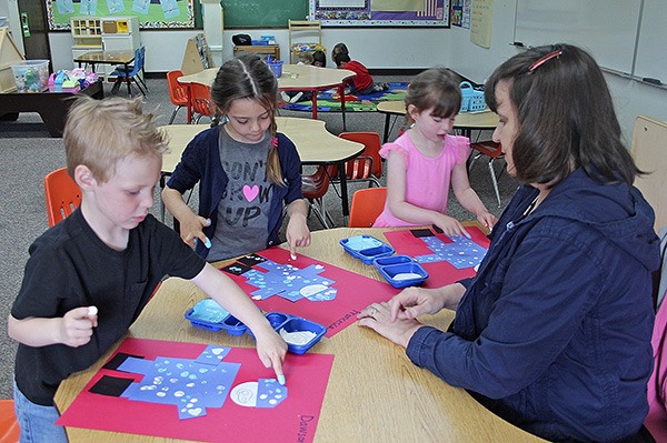 Teacher Robin Breakey watches pre-school students as they complete an art project. They are making Navy sailors that will be displayed during an upcoming band concert.