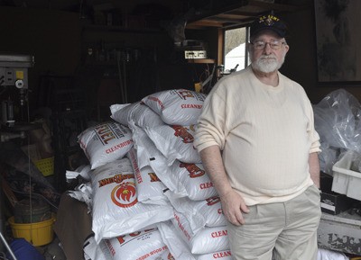 Port Orchard resident Glover “Leon” Ashlock leans against a few tons of wood pellets stored in his garage. The stove fuel was bought with aid funds from the Kitsap County Veterans Assistance program.