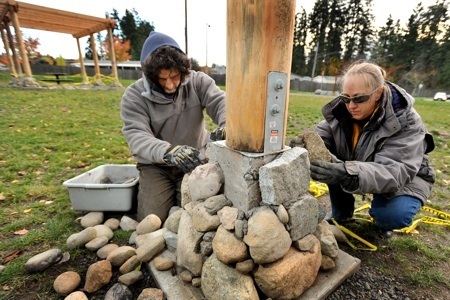 Landscape architects Brad Pugh and Laurie Larson work on rock placement for the footings of a pergola at Poulsbo's Centennial Park Wednesday.