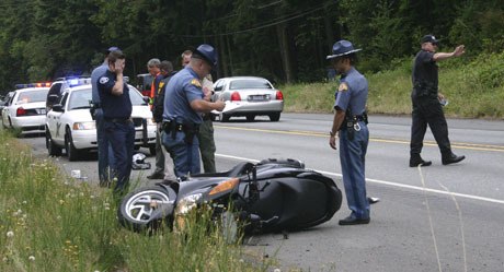 State patrol investigators review a wrecked scooter following a chase Tuesday where a one-armed man claimed he had been shot and then ran from law enforcement.