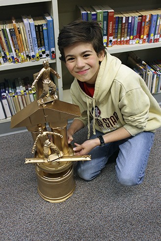 Aydan McGathey poses with his Earth Day creation made of recycled parts.