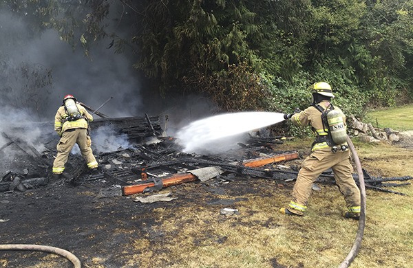 NKF&R Lieutenant Alex Hickey and Firefighter Tyler Horner make sure any remaining embers are out within the collapsed remains of a barn that was burned by its owner near Port Gamble on Sept. 15.
