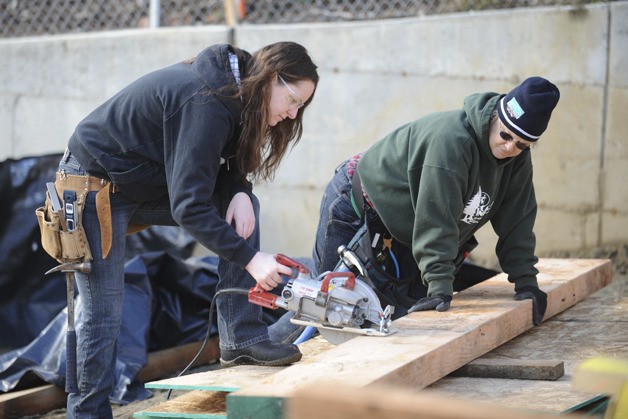 Tina Moyer cuts a beam with the help of Robin Jones at the Ohio Avenue building site
