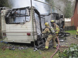 NKF&R Firefighters Kyle Cetnarowski and Ryan Buchanan snuff hot spots remaining in a travel trailer that burned between Kingston and Poulsbo on Thursday morning.