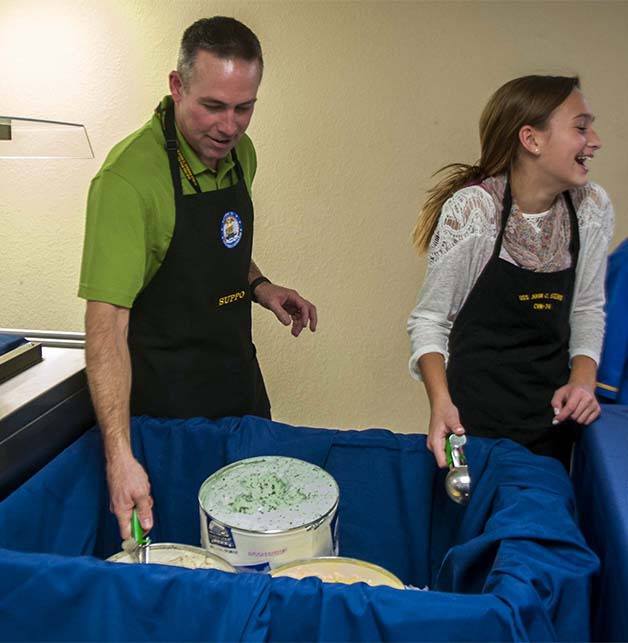 Dan Davidson and his daughter serve ice cream to sailors during a Thanksgiving meal for those assigned to the Nimitz-class aircraft carrier USS John C. Stennis.