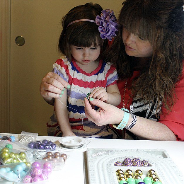 Nicole Neumann works on beading a necklace with her daughter