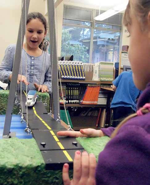 Pearson Elementary students Ellie Navarro pushes a toy truck across a model cable bridge