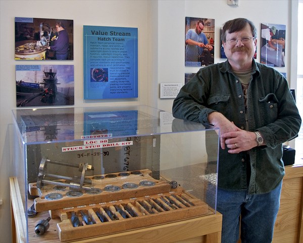 Navy Museum volunteer Randy Tacey stands next to an industrial stud removal kit on loan from Shop 38. Tacey retired from shop after more than two decades of service. His son