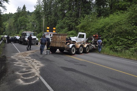 Crews work to clean up about 20 gallons of fuel spilled after a truck struck a car on State Highway 308 Monday afternoon. The collision and spill closed both lanes for nearly two hours.