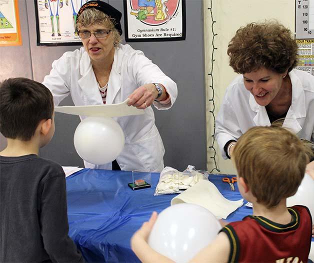 Silver Ridge Elementary teachers work as 'mad scientists' during a family night at the school. The pair taught students about static electricity by rubbing balloons on wool.