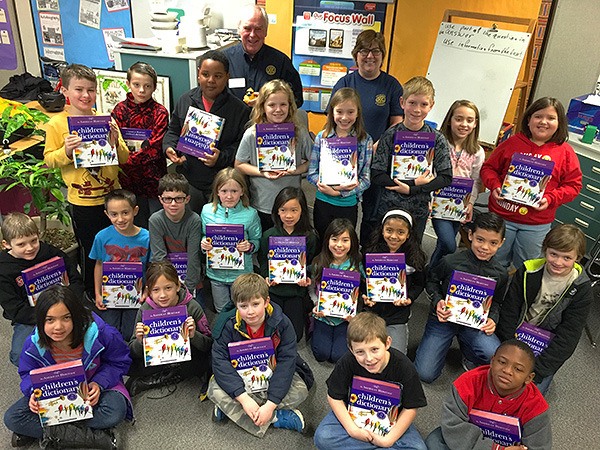 Silverdale Rotarians Peter Matty and Mary Hoover stand with a group of Emerald Heights third-graders as the children show their new dictionaries. Each year