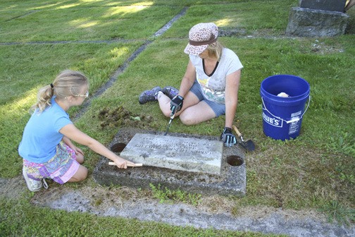 Volunteers work to clean up the memorials of veterans in Ivy Green Cemetery on Aug. 5. More than 200 community members showed up to beautify the grounds and provide greater honor to the dead laid to rest there.