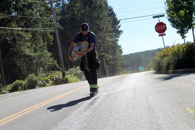 Firefighter Shane Anderson cleans up a fuel spill on Noll Road