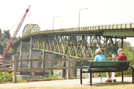 A couple watches as construction begins on the historic Manette Bridge.