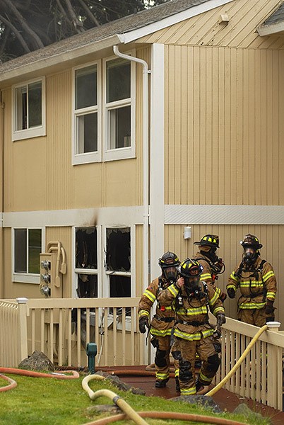 Firefighters walk near a fire-damaged apartment at Centennial Apartments in Bremerton on April 23.