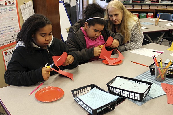 Sisters Aniah and Olivia Smaw cut out pieces for their “ladybug clock” at a Math Blast event. Armin Jahr Elementary hosted the event for families to explore math together.