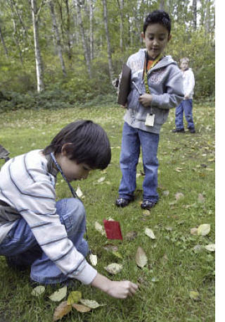 Jalen Jones places a red marker flag next to a pile of dog poop as Malo Castro looks on. The Emerald Heights Elementary students visited Island Lake Park Wednesday doing field tests on the trails.