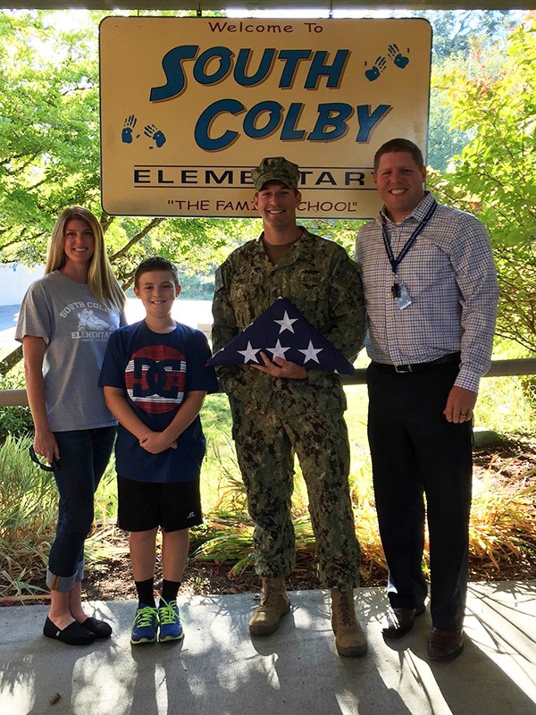 The Wheeler family poses with principal Joe Riley and the flag Chief Doug Wheeler donated to South Colby Elementary.