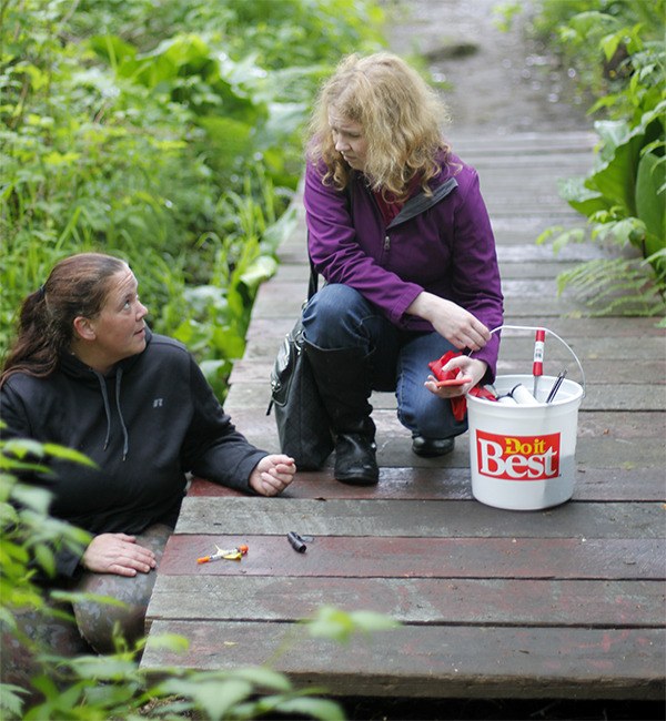 Toni Bourner and April Ferguson  pick up drug paraphernalia from the trail behind Village Green on May 4.