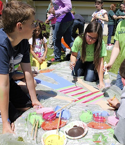 Peace Lutheran students work on a paint project on the front lawn of the school.