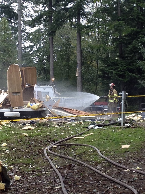 A North Kitsap Fire & Rescue firefighter hoses down a travel trailer destroyed by a propane explosion