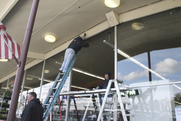Dahl Glass of Silverdale installs new windows at Red Apple Market in Poulsbo Monday. The windows were shot at