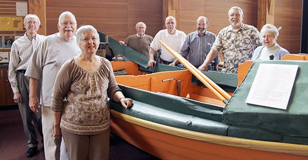Members of the Poulsbo Historical Society board of directors pose around a restored codfish dory that is part of the collection of the new Poulsbo Maritime Heritage Museum