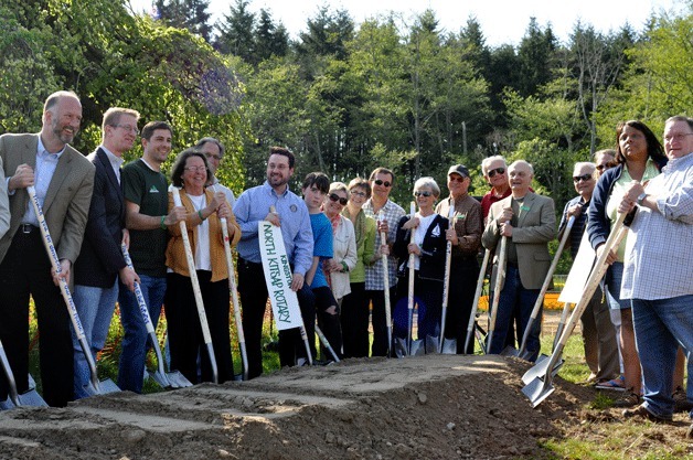 Community members dig into dirt at the groundbreaking ceremony for the new Village Green Community Center