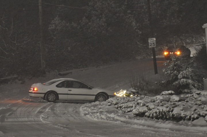 One car spins its way up 1st Street in Bremerton Wednesday morning as another struggles to back out of the ditch.
