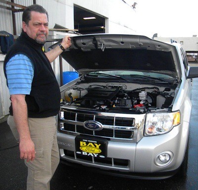 Bay Ford Fleet Manager Ross Wood inspects the engine of a Ford Escape SUV identical to that purchased by the Port Orchard Police Dept.