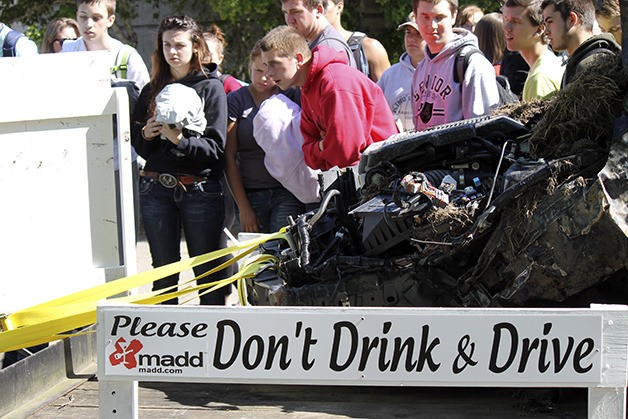 Klahowya Secondary School seniors read details and inspect a car involved in a fatal drunk driving collision. The display was part of a mock crash event intended to educate students right before prom and graduation about the devastating impact of drunk driving.